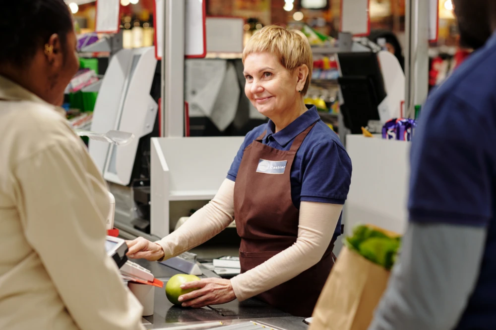 Abteilungsleitung sitzt an der Kasse und scannt Produkte