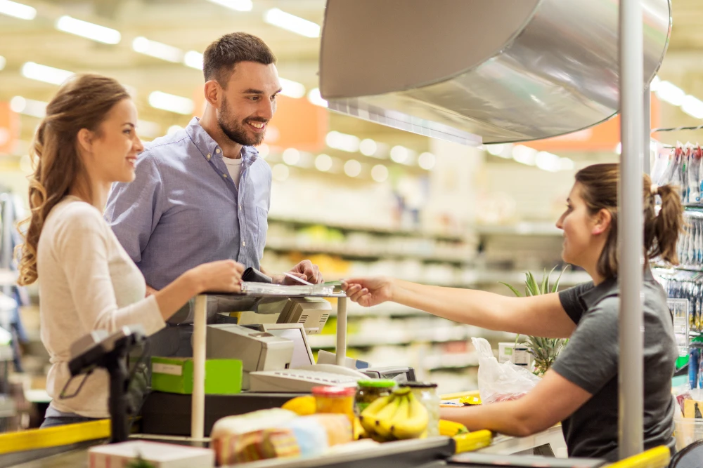 Abteilungsleitung sitzt an der Kasse und spricht mit Kunden